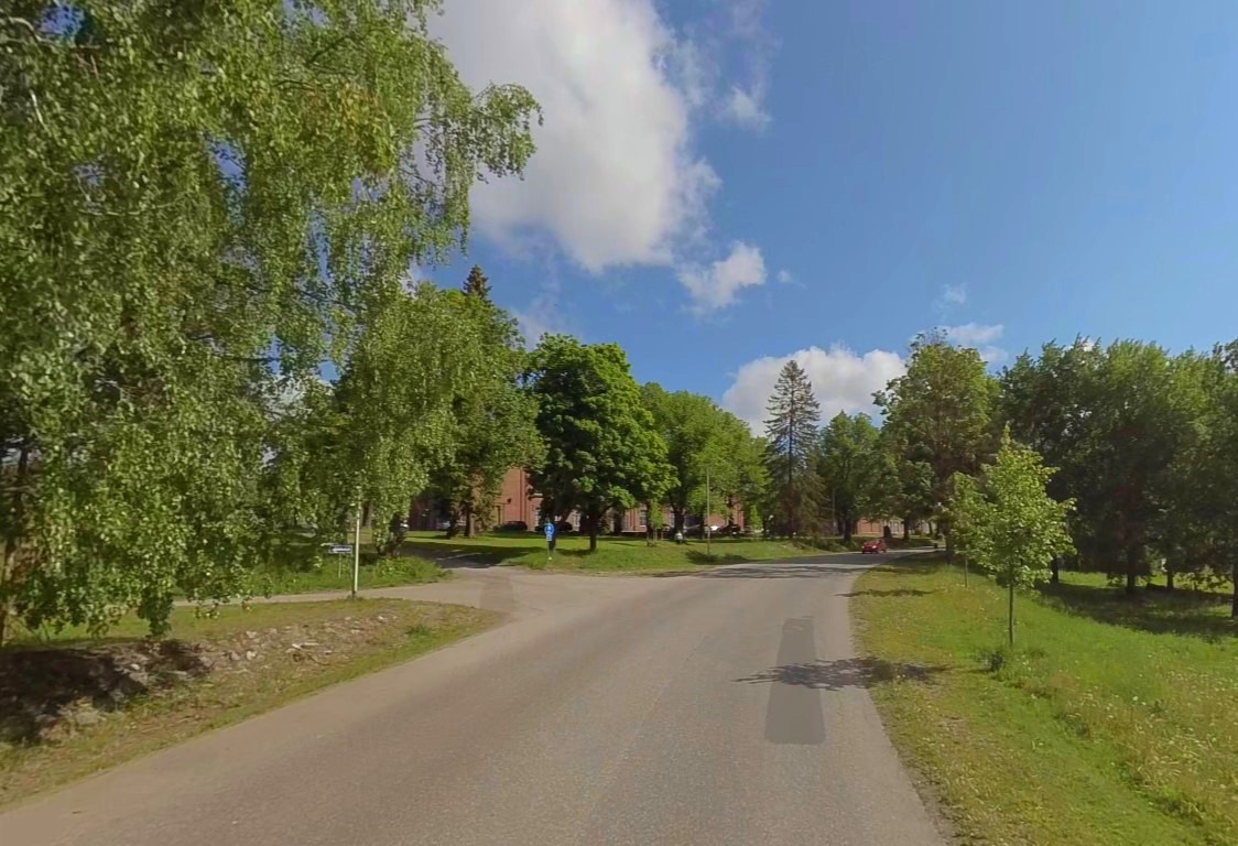 Kesäinen maisemakuva Kasarmikadun alusta Rakuunamäen suuntaan. Vihreitä puita, nurmikkoa, takana punaisia tiilirakennuksia.